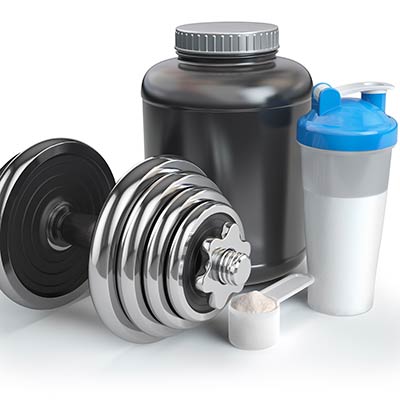 Whey protein powder in a scoop with shaker and container